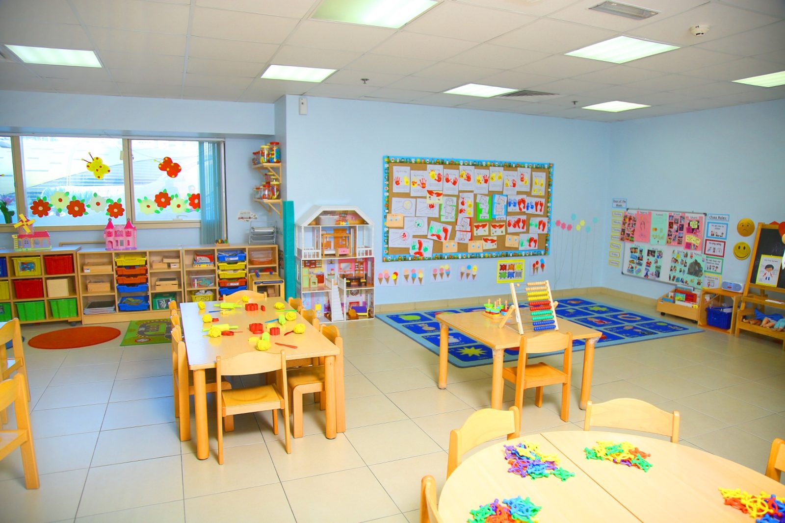 The Pre-KG room, with blue and yellow child-height tables, low shelving and display boards